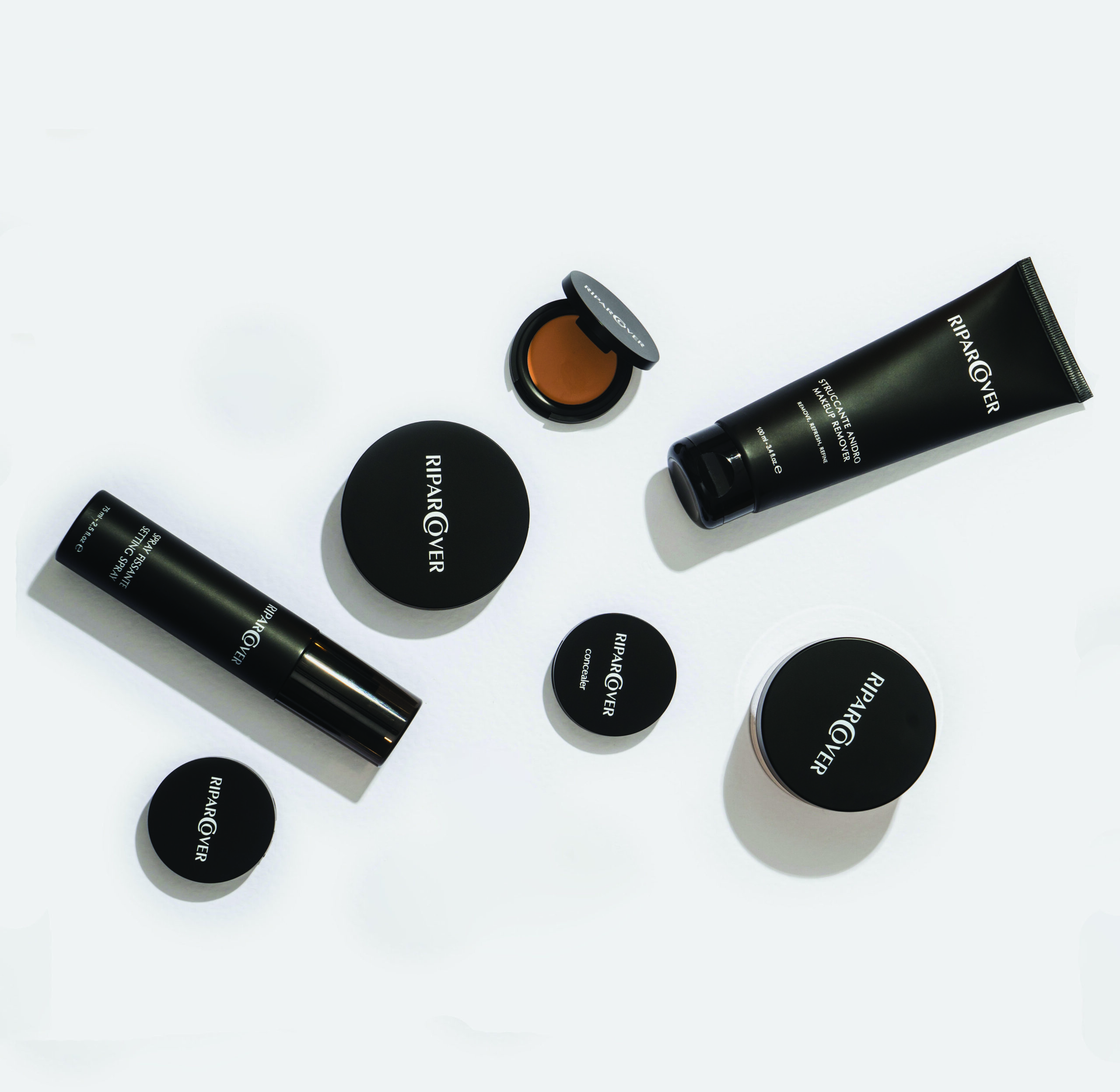 Prodotti cosmetici RiparCover in packaging nero minimal: fondotinta, correttore, spray e struccante.