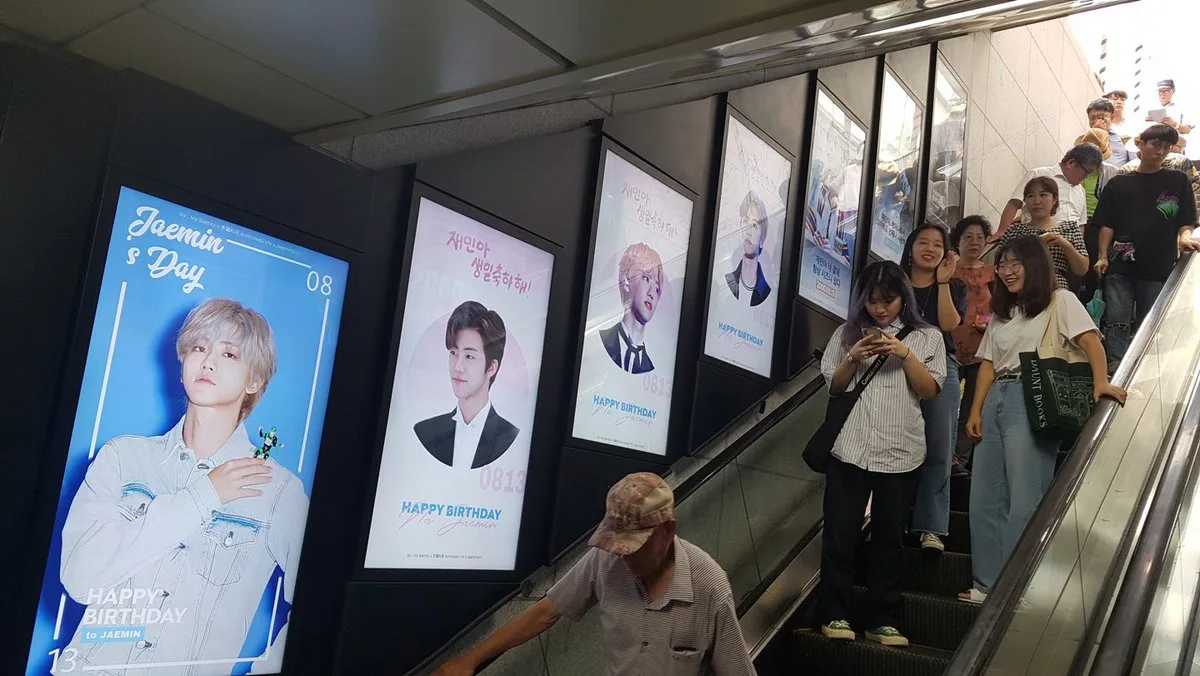 Manifesti pubblicitari di idol K-pop esposti lungo le scale mobili della metropolitana di Seoul.