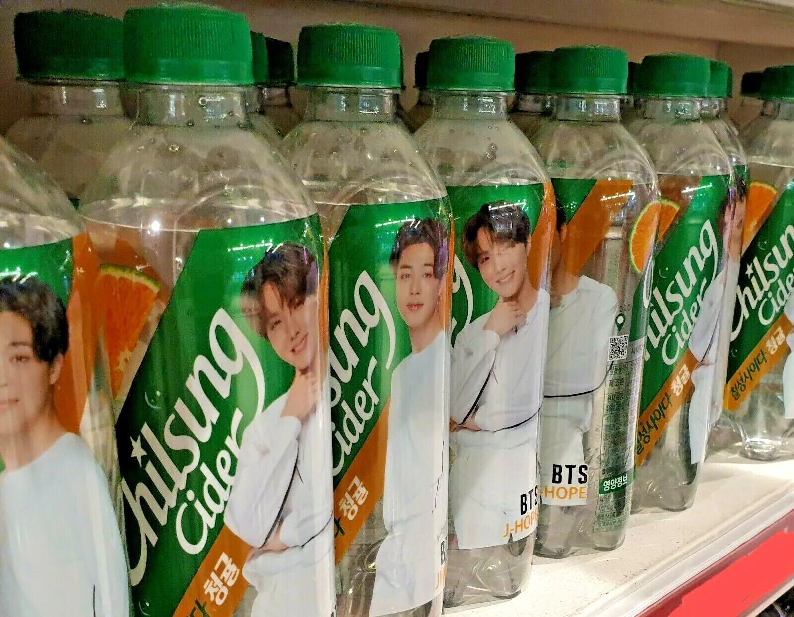 Immagine dello scafale di un supermercato con l'edizione limitata del packaging di Chilsung Cider con i volti dei membri dei BTS.