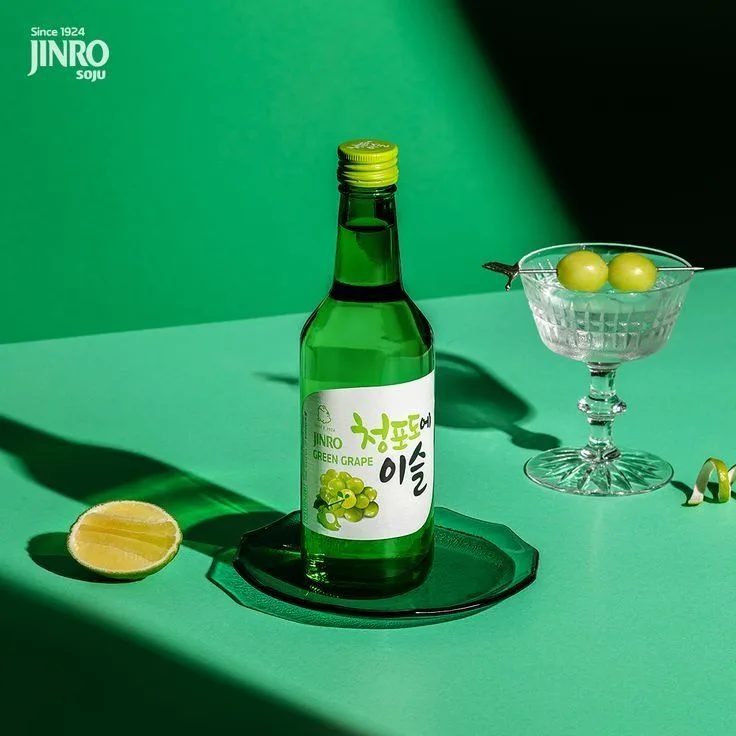 Immagine di HiteJinro soju all'uva su un tavolo verde con sfondo verde.
