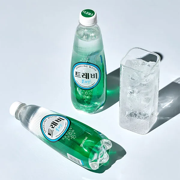 Immagine di due bottigliette di acqua coreana Trevi e un bichiere di acua e ghiaccio su sfondo celeste.