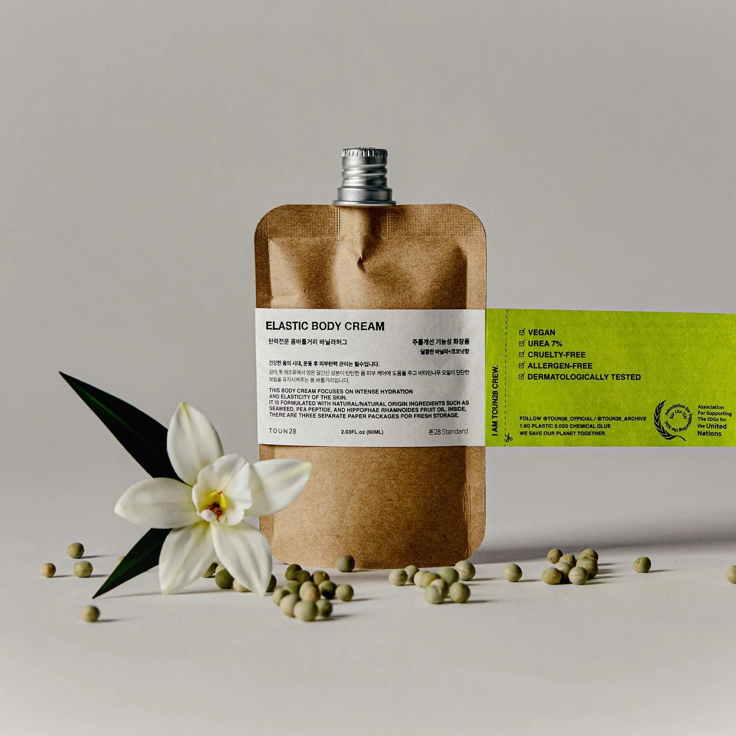 Packaging TOUN28 Elastic Body Cream kraft con etichetta bianca, fiori, bacche di vaniglia e tappo a vite.