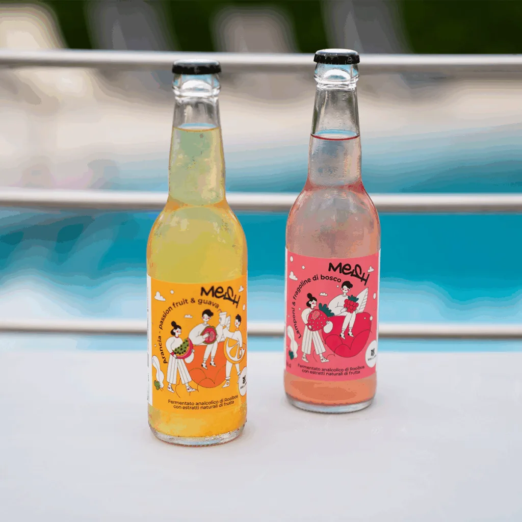 Clear bottles of Meah with passion fruit & guava and wild berry flavors, condensation visible, pool in background