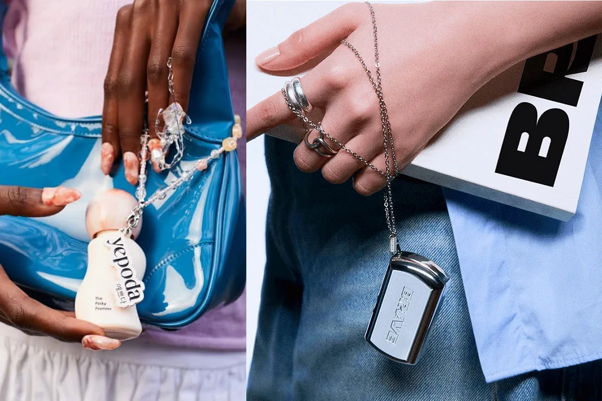 Mani con accessori cosmetici: flacone Yepoda su borsa blu e ciondolo cromato BRAVE con libro e jeans.