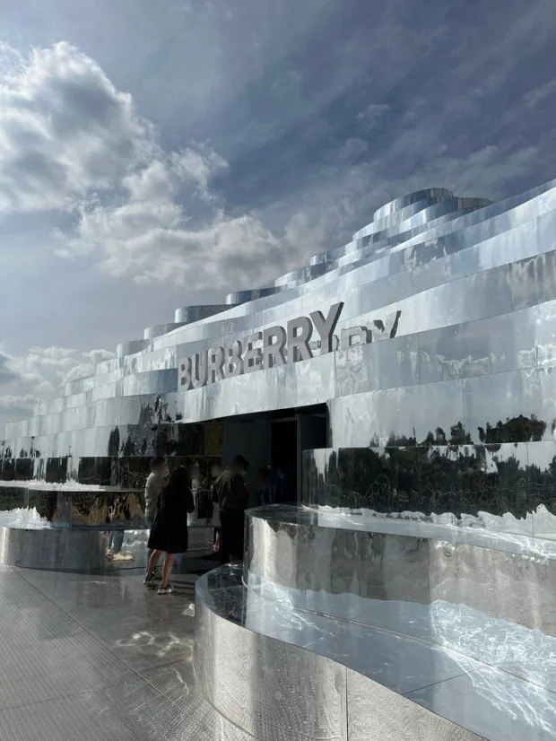 Ingresso Burberry a Jeju con pareti esterne specchiate che riflettono il paesaggio montano circostante