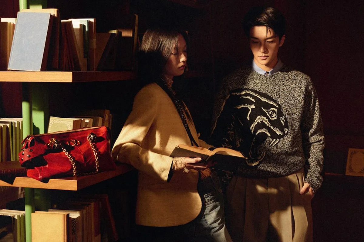 Yidan Huang e Zen Yue in una libreria d'atmosfera per la campagna Valentino Qixi Festival 2026 con borsa rossa in vista.