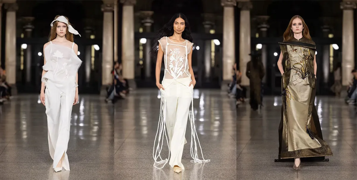 Tre modelle in passerella alla Milano Fashion Week Keqiao 2025 con abiti trasparenti, frange e dettagli botanici ricamati.
