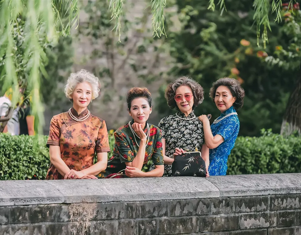 Quattro donne senior cinesi eleganti in abiti tradizionali qipao mettono in posa all'aperto.