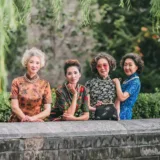 Quattro donne senior cinesi eleganti in abiti tradizionali qipao mettono in posa all'aperto.