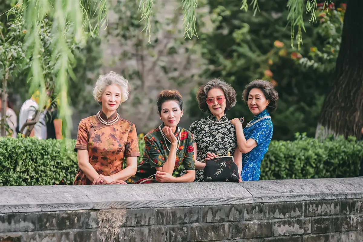 Quattro donne senior cinesi eleganti in abiti tradizionali qipao mettono in posa all'aperto.